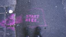 "start here" written on the ground with pink chalk