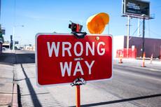 Wrong way sign, written in white on a red rectangle with an orange light
