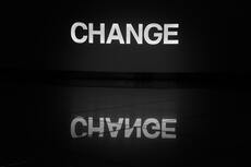 Le mot "change" en lumière blanche et reflété sur un sol carrelé.