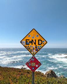 "End" road sign partially covered with a lot of stickers